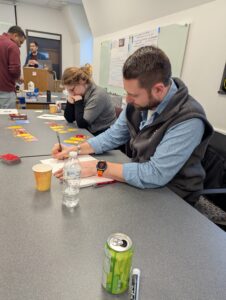 A man and a woman sitting at a table, taking notes and looking at game cards.